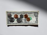 Exploring Top Scholarships for International Students from Africa A U.S. one-dollar bill lies flat on a white surface, with coins—including pennies, nickels, dimes, and quarters—arranged on top under bright lighting, symbolizing opportunities like scholarships for international students from Africa.