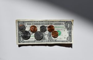 Exploring Top Scholarships for International Students from Africa A U.S. one-dollar bill lies flat on a white surface, with coins—including pennies, nickels, dimes, and quarters—arranged on top under bright lighting, symbolizing opportunities like scholarships for international students from Africa.