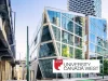 University Canada West Scholarships for International Students 2025 | Eligibility & How to Apply A modern glass building with angular features reflects city skyscrapers beside an elevated roadway. In the foreground is the University Canada West logo, highlighting a red maple leaf and promoting a scholarship for international students.