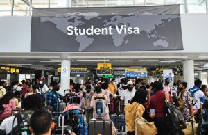 Nigerian Student Visa Guide 2025: Requirements and Steps A crowded airport terminal buzzes with students from diverse backgrounds, many aiming for a Nigerian student visa. Above them, a world map sign reads Student Visa as they carry their luggage to new academic journeys.