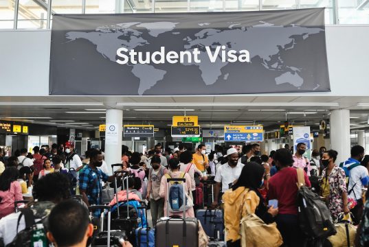 Nigerian Student Visa Guide 2025: Requirements and Steps A crowded airport terminal buzzes with students from diverse backgrounds, many aiming for a Nigerian student visa. Above them, a world map sign reads Student Visa as they carry their luggage to new academic journeys.