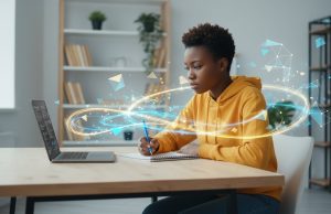 How to write a Scholarship Essay: Tips & Examples for African Students A person in a yellow hoodie works at a desk with a laptop and notebook, surrounded by digital, glowing geometric graphics—perfectly capturing the focus needed to master scholarship essay examples for African students.