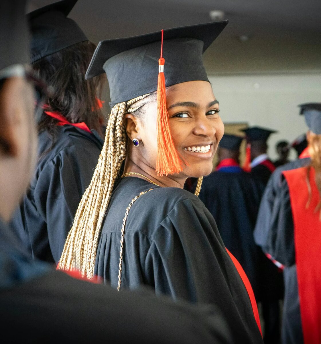 A graduate smiling confidently in cap and gown, celebrating their academic achievement at a graduation ceremony, representing the success of minority students pursuing MBA scholarships.