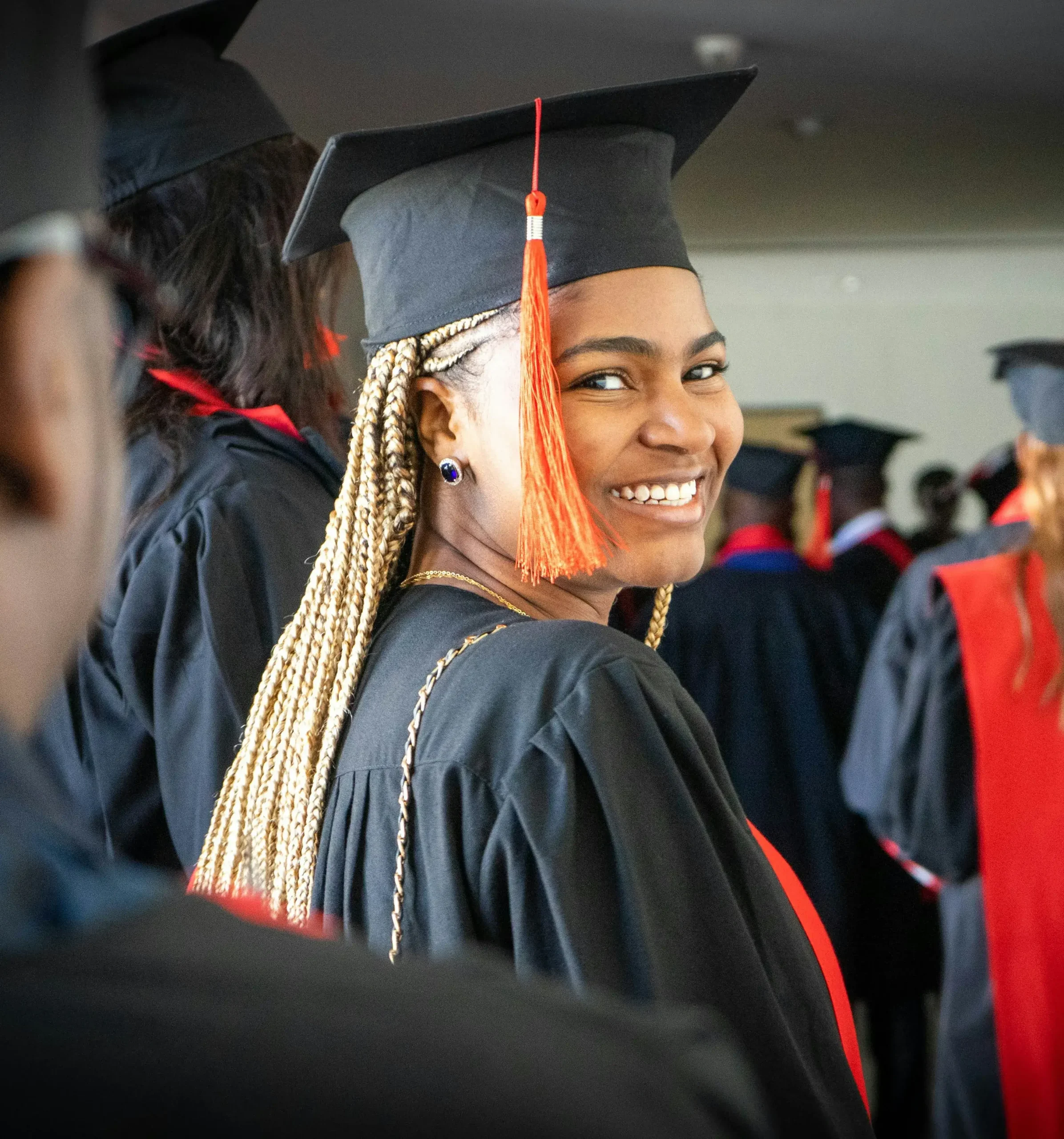 A graduate smiling confidently in cap and gown, celebrating their academic achievement at a graduation ceremony, representing the success of minority students pursuing MBA scholarships.